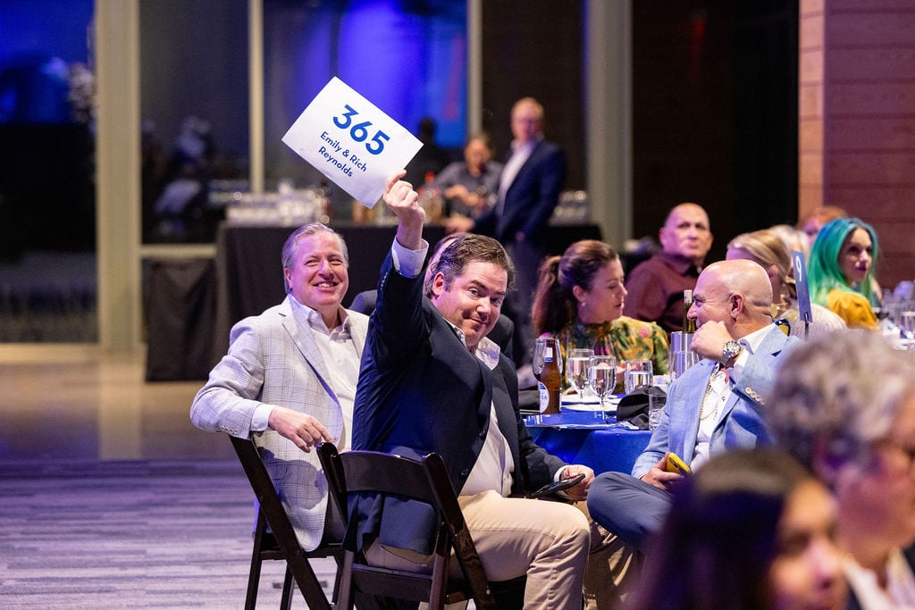 A guest raising a bid paddle during the Greater Heights Night live auction